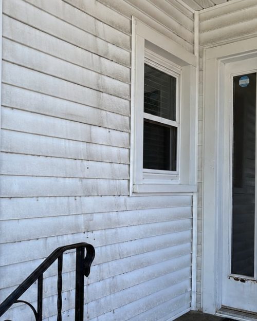White siding and a front entry with dirt and green streaks